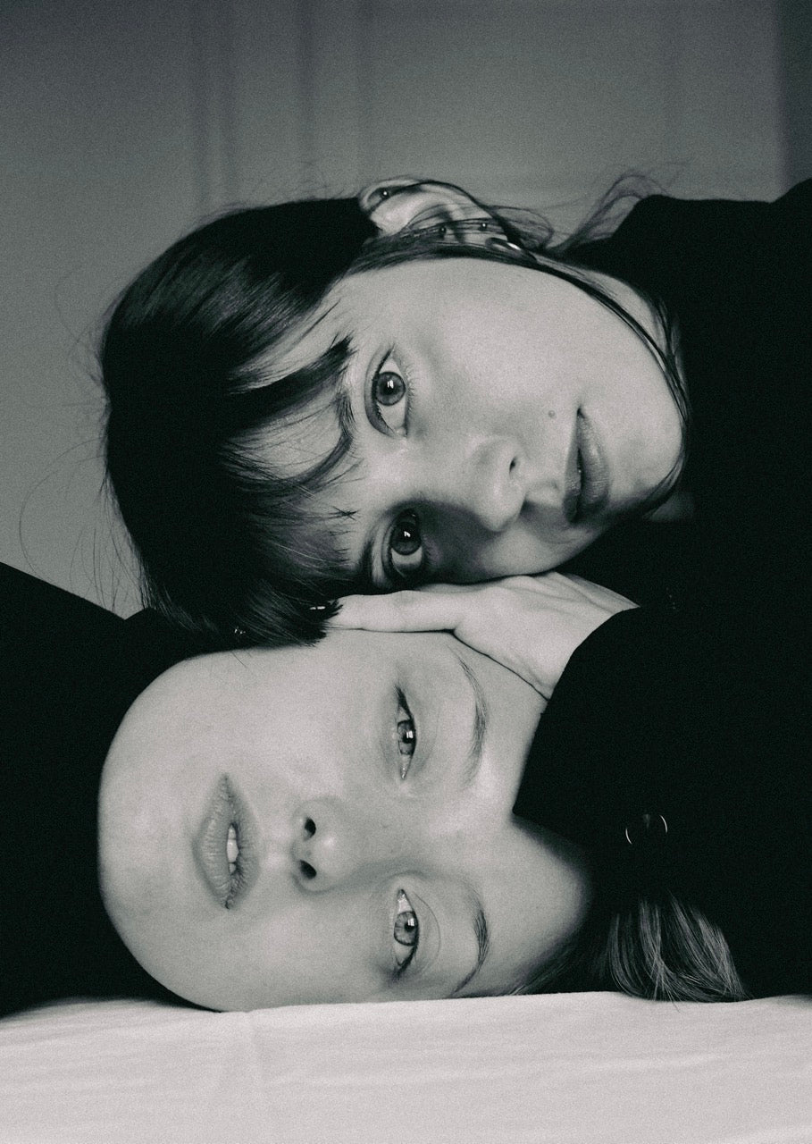 two female heads on top of one another placed on a table,  looking straight to the camera